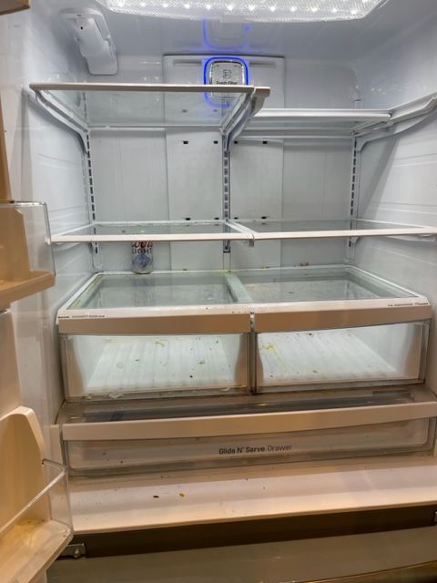 Empty refrigerator interior with glass shelves and drawers.