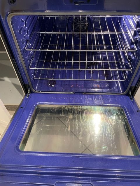 Open blue oven interior with racks and a glass door.