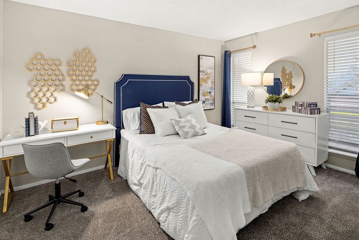 a bedroom with a large bed, dresser, chair, and lamps.