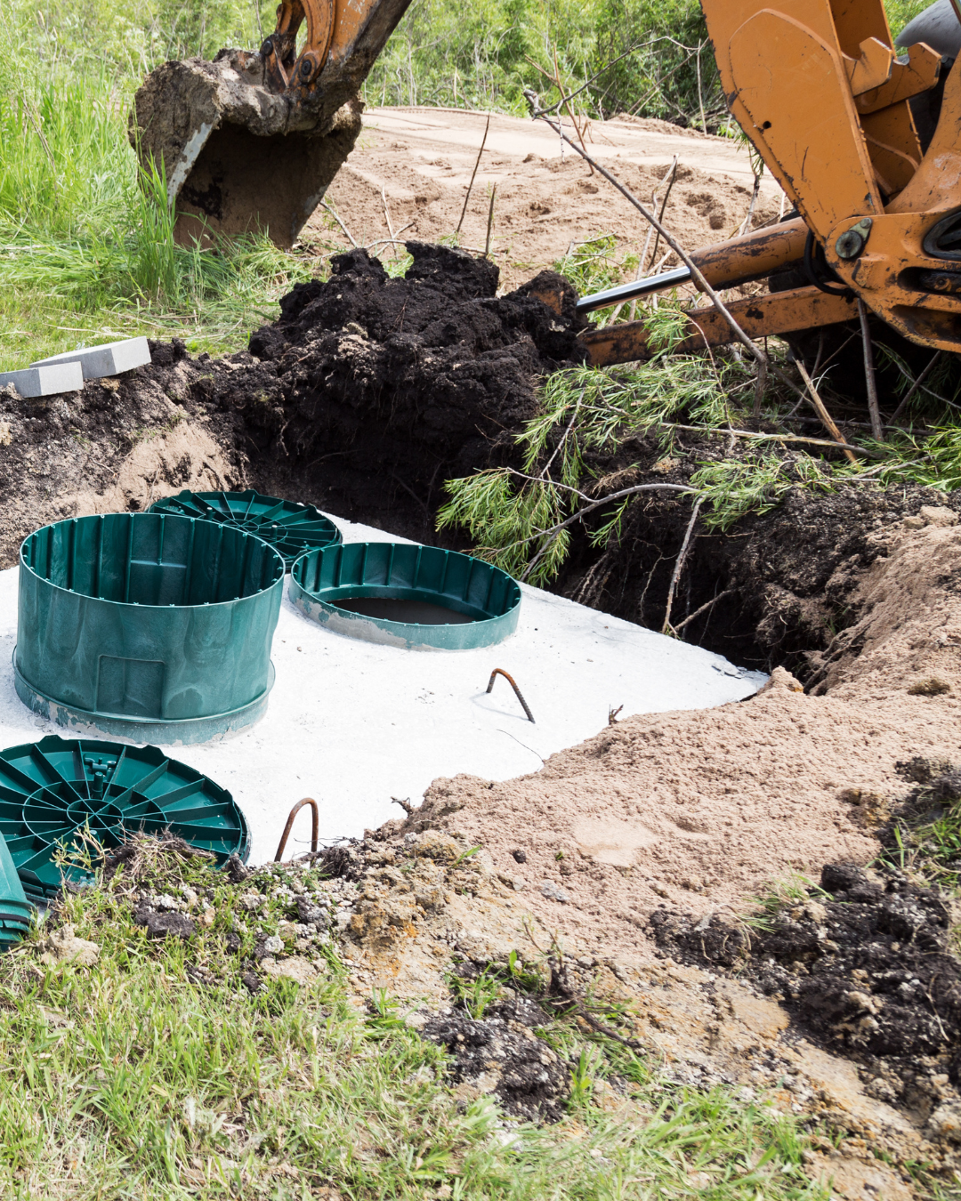 A bulldozer is digging a hole in the ground to install a septic tank.