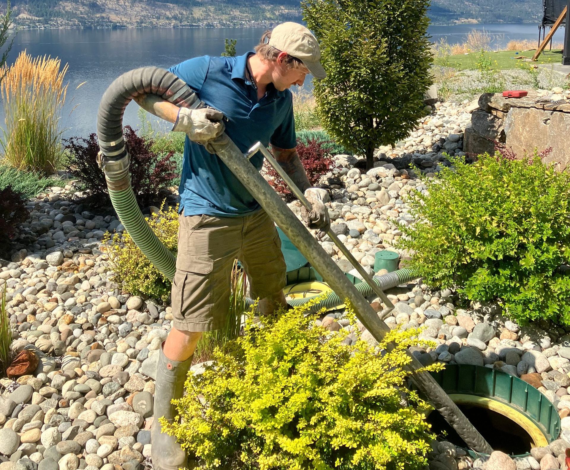 A man is pumping water into a septic tank with a hose.