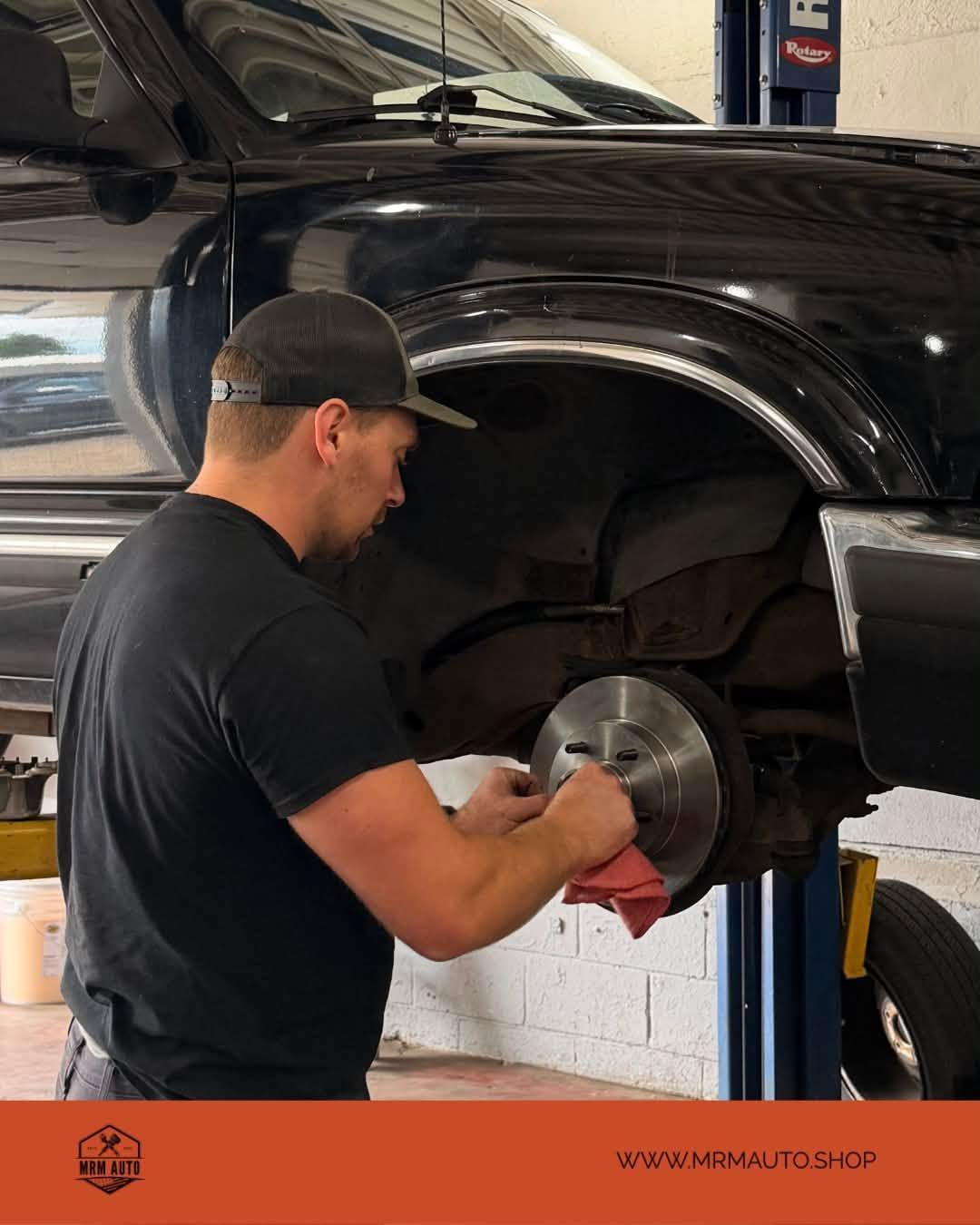Mechanic working on a black truck’s brake rotor in an auto shop | MRM Auto LLC