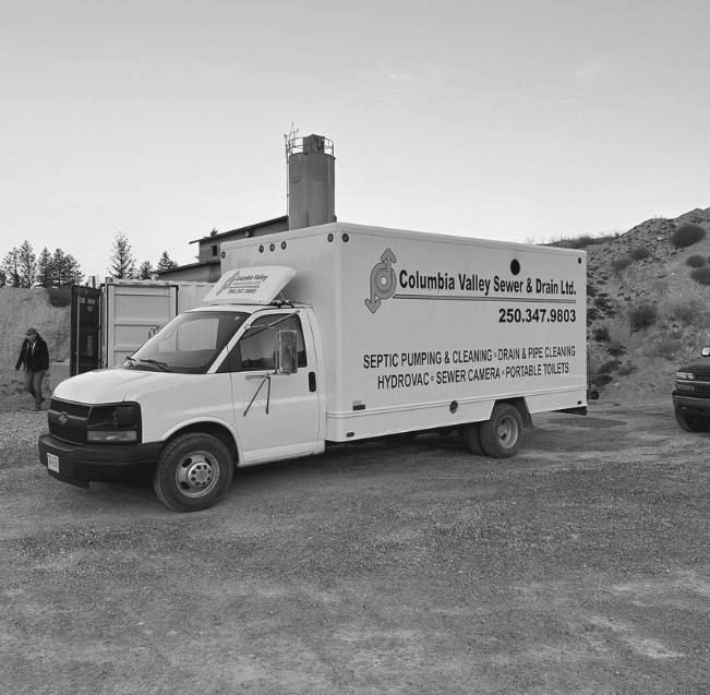 A columbia valley sewer and drain truck is parked in a dirt lot