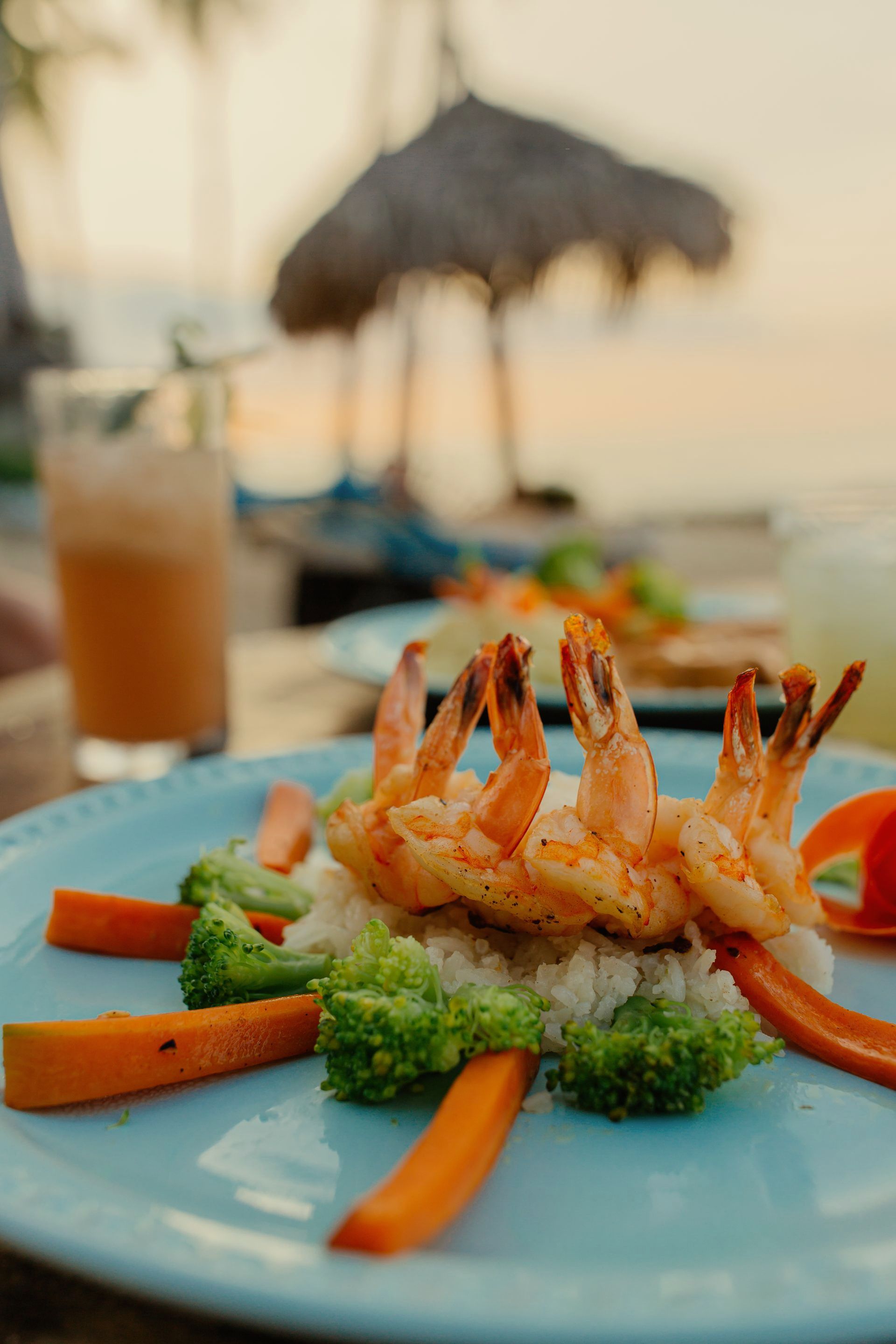 Un plato de comida con camarones, brócoli, zanahorias y arroz en una mesa.