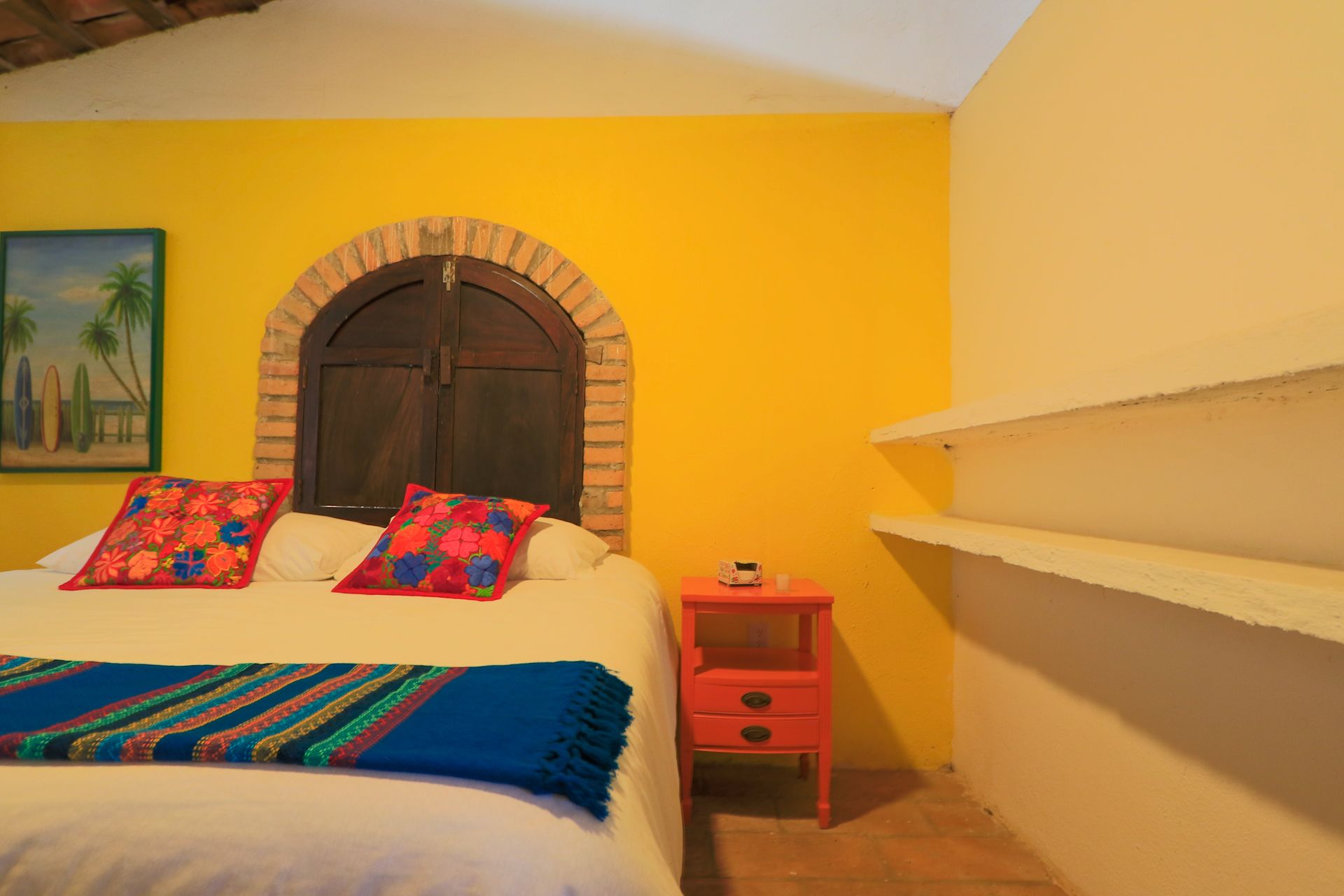 Un dormitorio con una cama, mesita de noche y paredes amarillas.