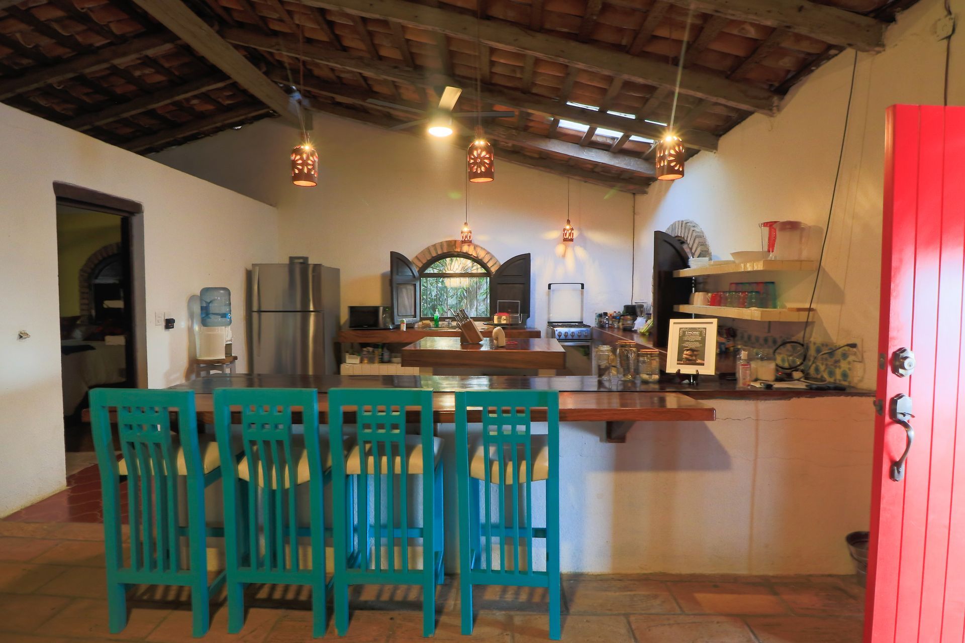 Una cocina con sillas azules y una puerta roja.