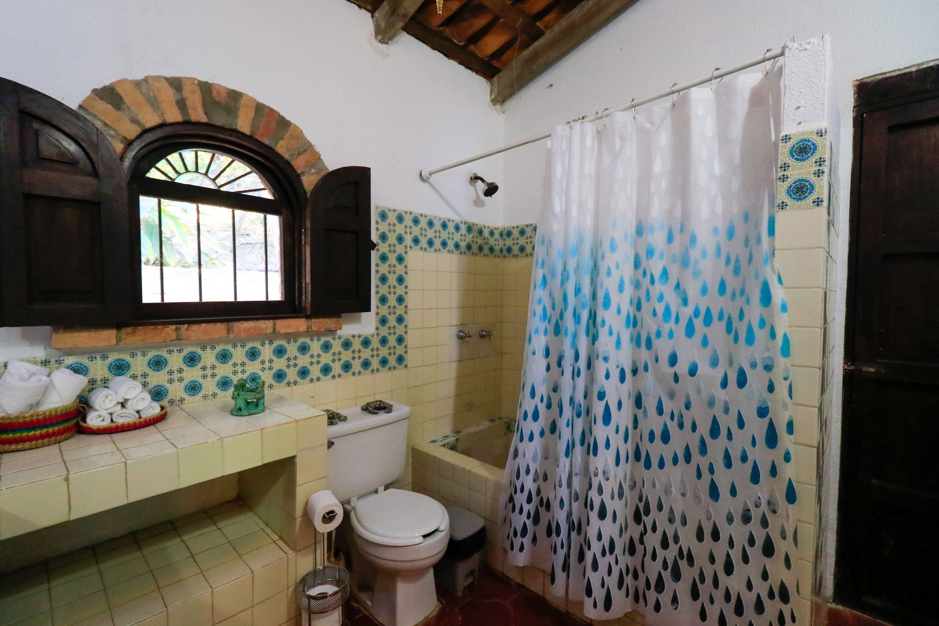 Un baño con inodoro, cortina de ducha, bañera y ventana.