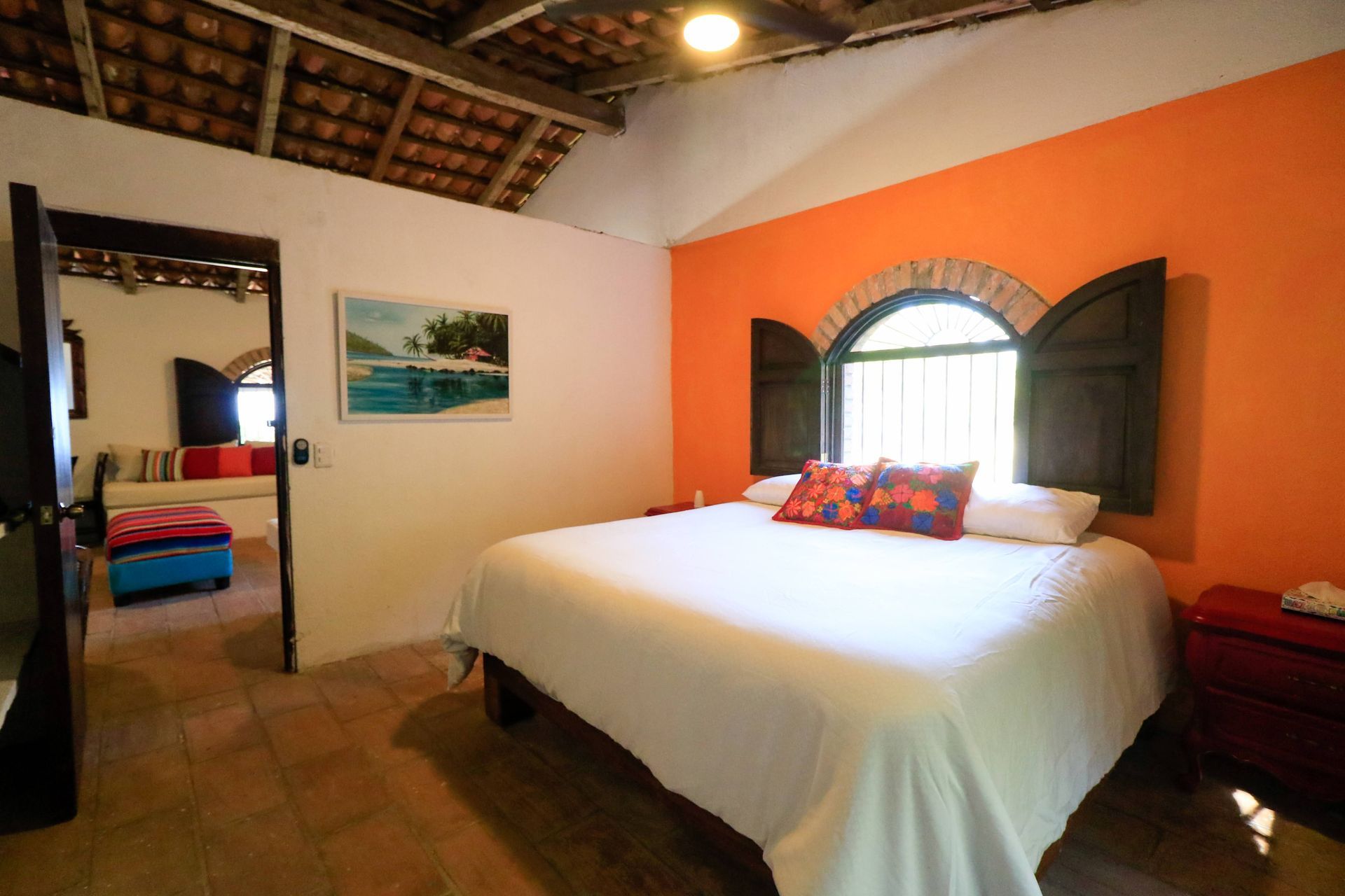 Un dormitorio con una cama king size y paredes naranjas.