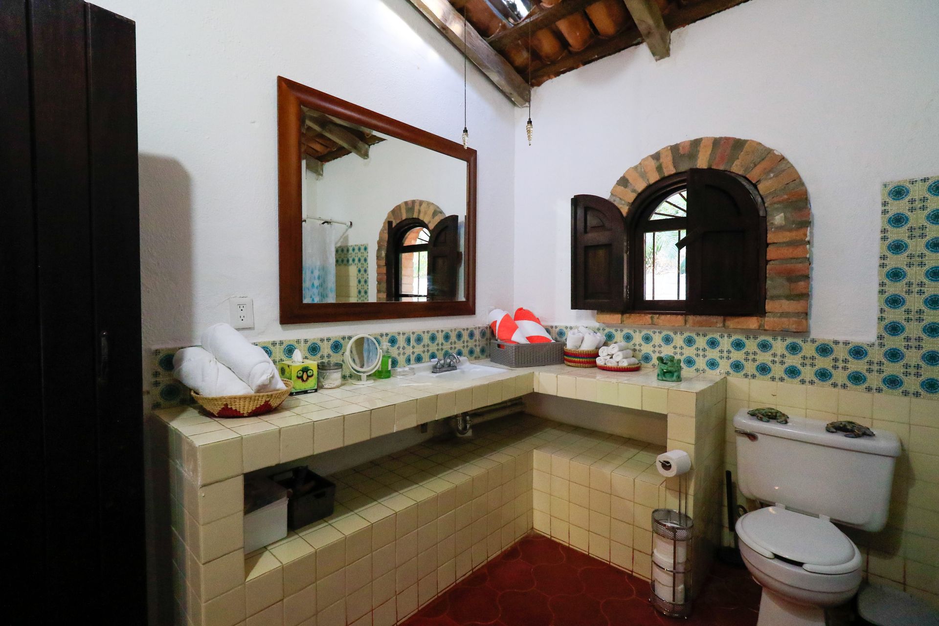 Un baño con inodoro, lavabo, espejo y ventana.