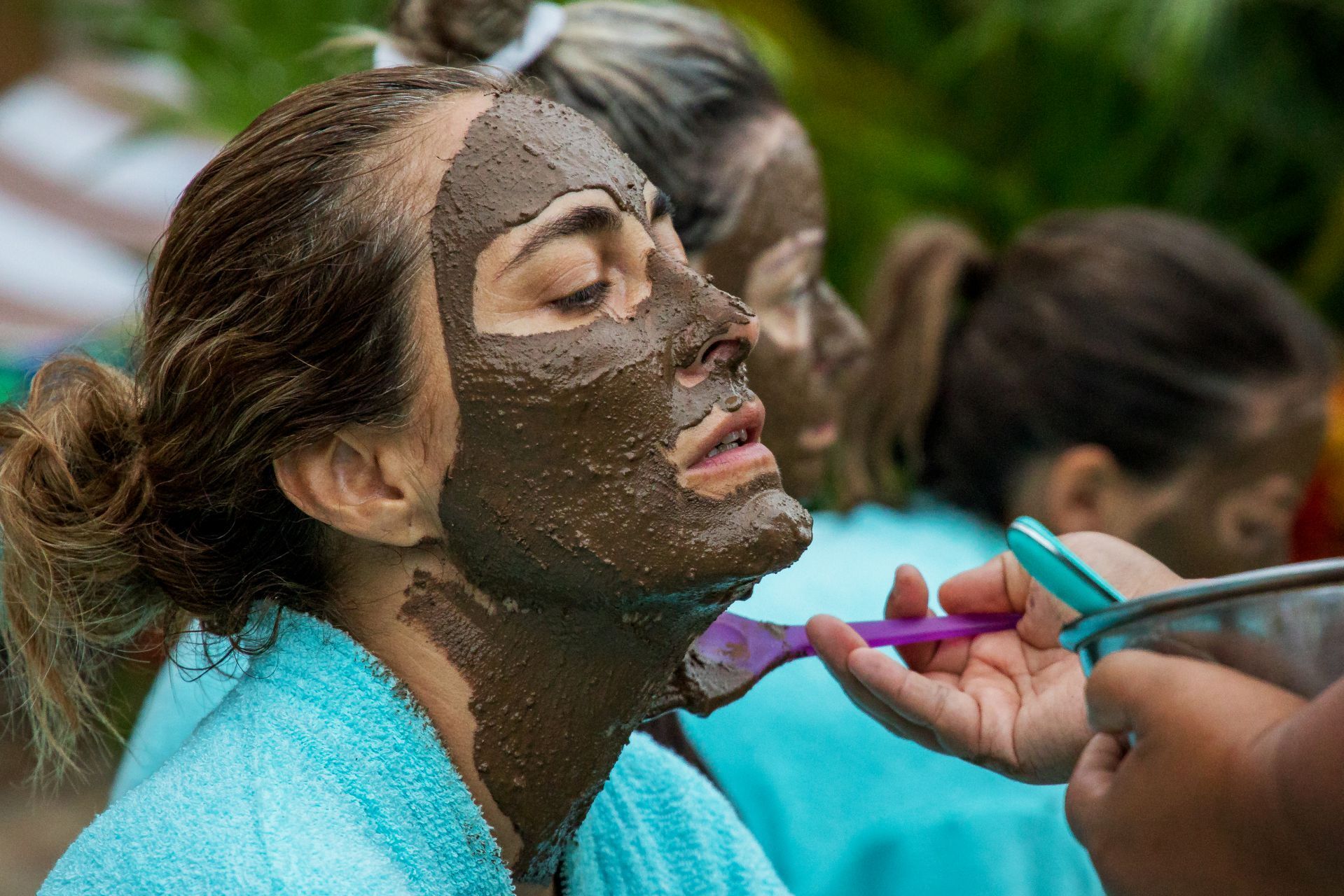 Una mujer se está poniendo una mascarilla de barro en la cara.