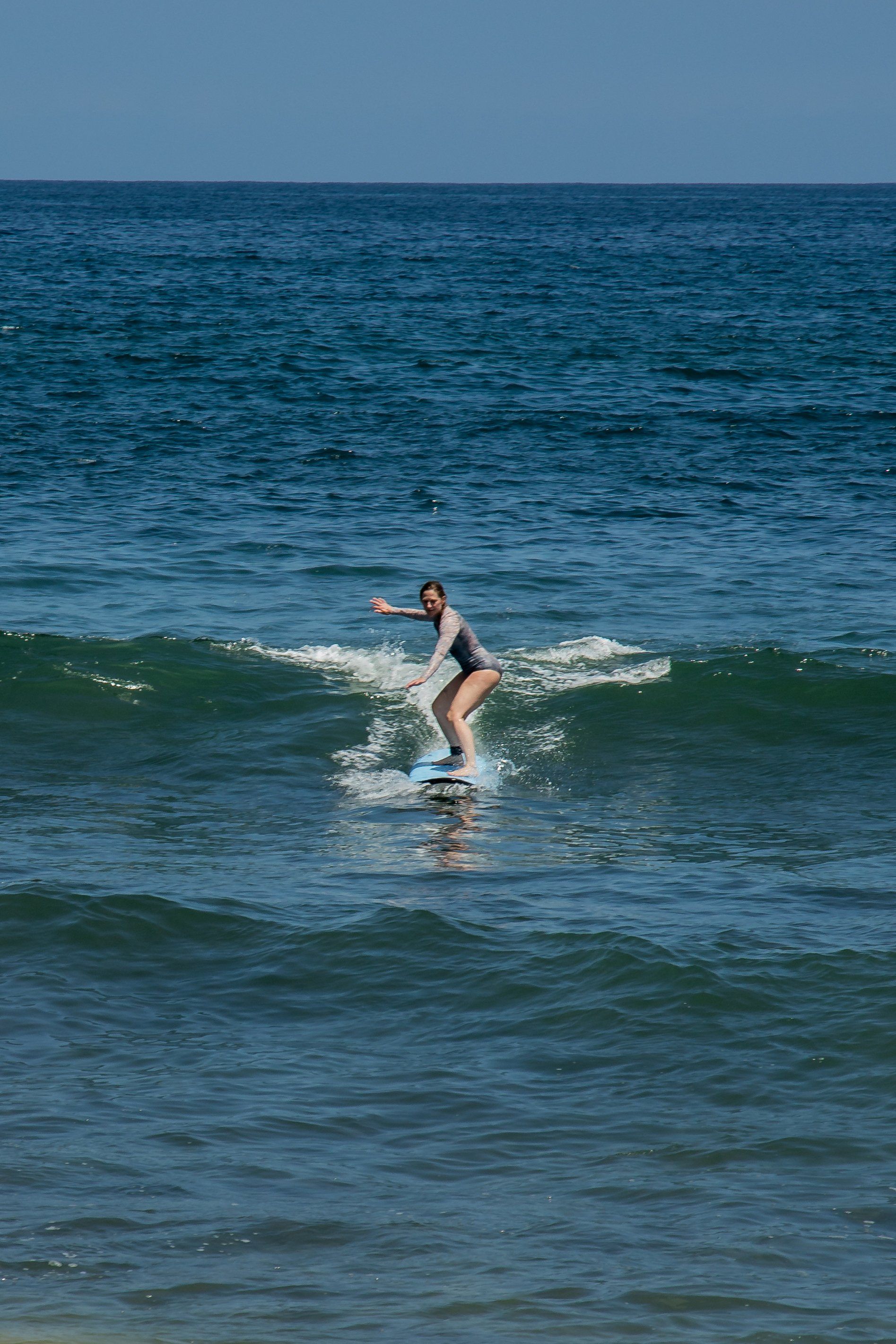 Una mujer está montando una ola en una tabla de surf en el océano.