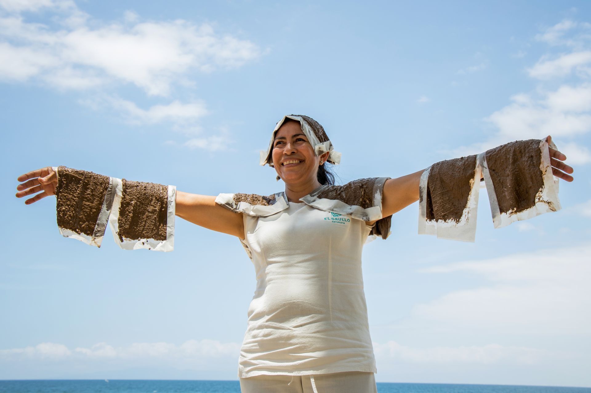 Una mujer está parada en una playa con los brazos extendidos.