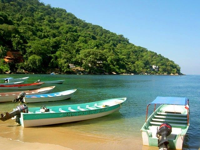 Una fila de barcos en una playa con uno que dice 'aventura' en él