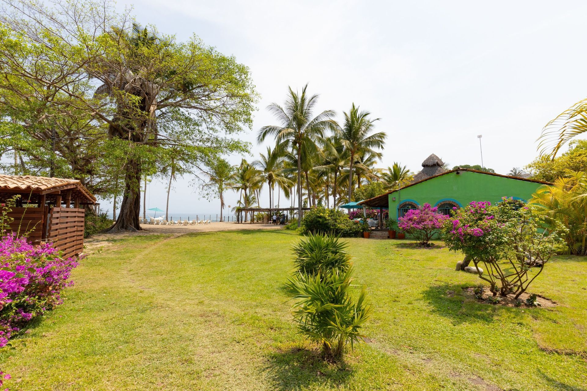 Una casa verde está rodeada de árboles y flores en un exuberante patio verde.