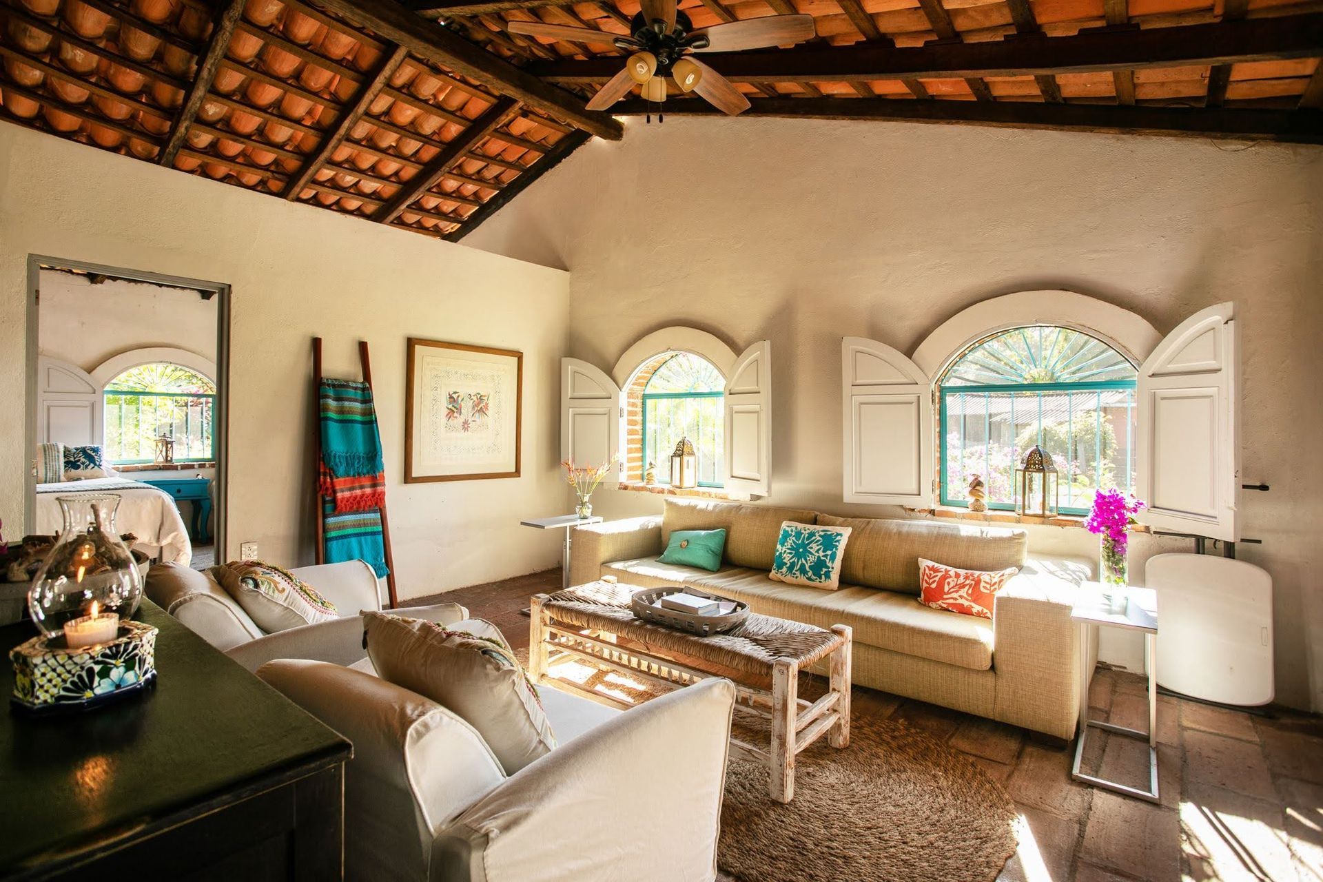 Una sala de estar con un sofá, sillas y persianas en las ventanas.