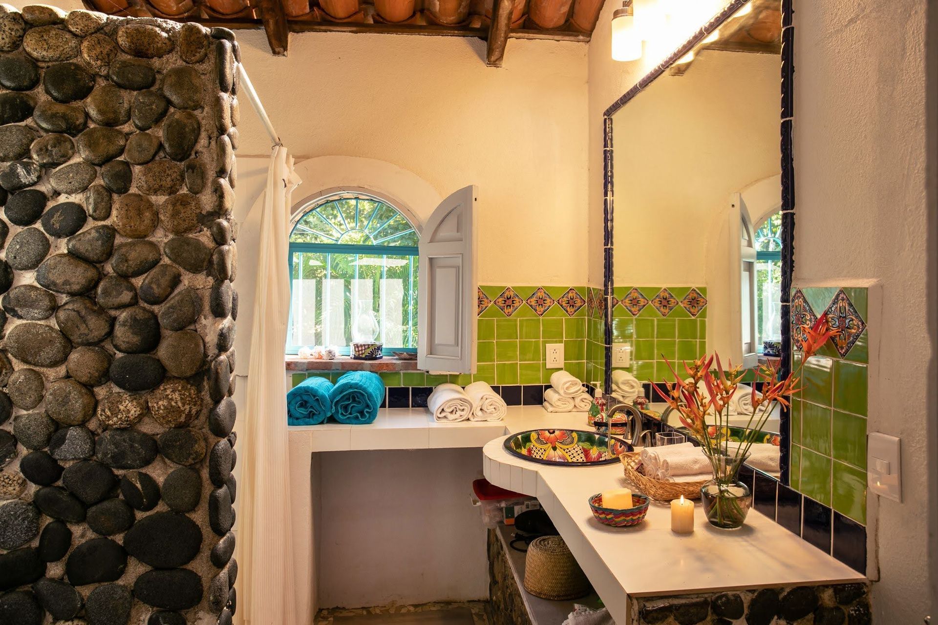 Un baño con azulejos verdes y una pared de piedra.