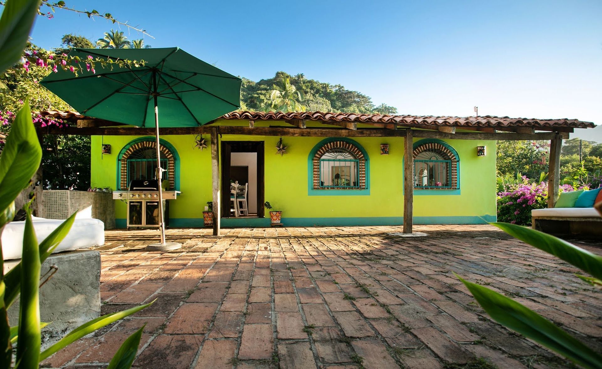 Una casa verde con una sombrilla verde delante de ella.