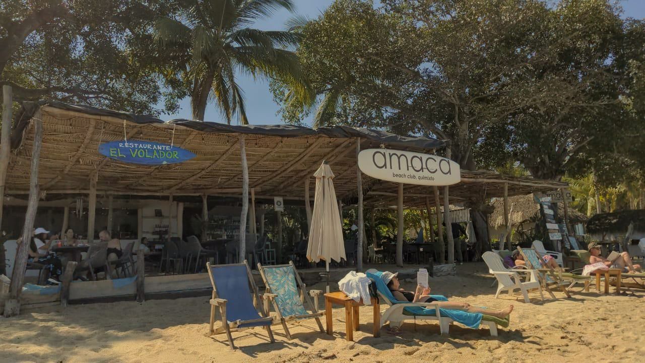Una playa con sillas y sombrillas frente a un restaurante.