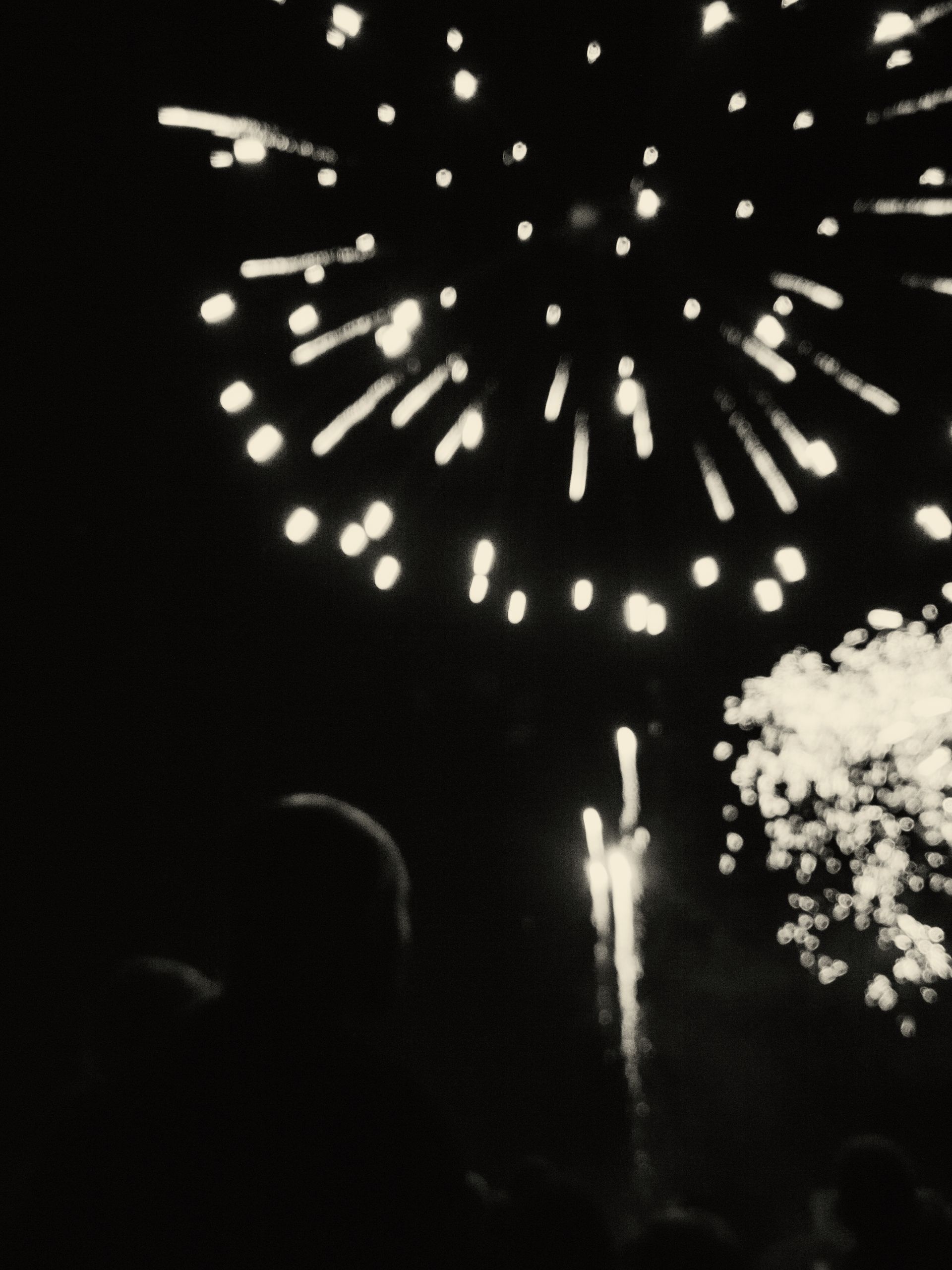 Una fotografía en blanco y negro de fuegos artificiales en el cielo nocturno.