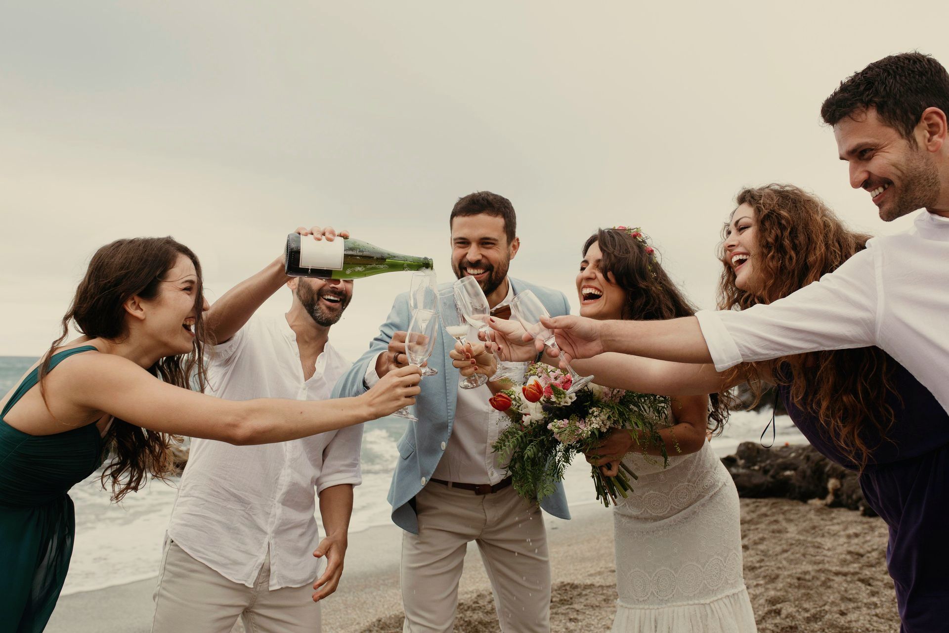 Un grupo de personas brinda con champán en la playa.
