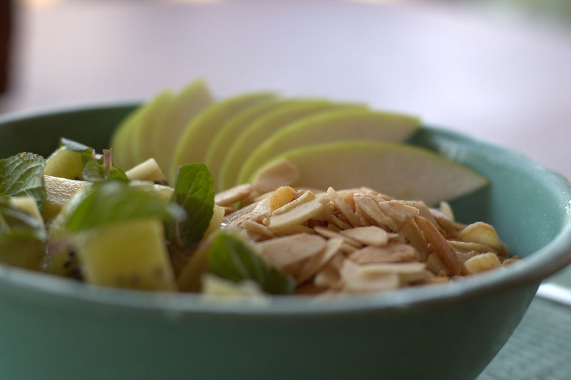 Un recipiente de comida con rodajas de manzana y almendras sobre una mesa.