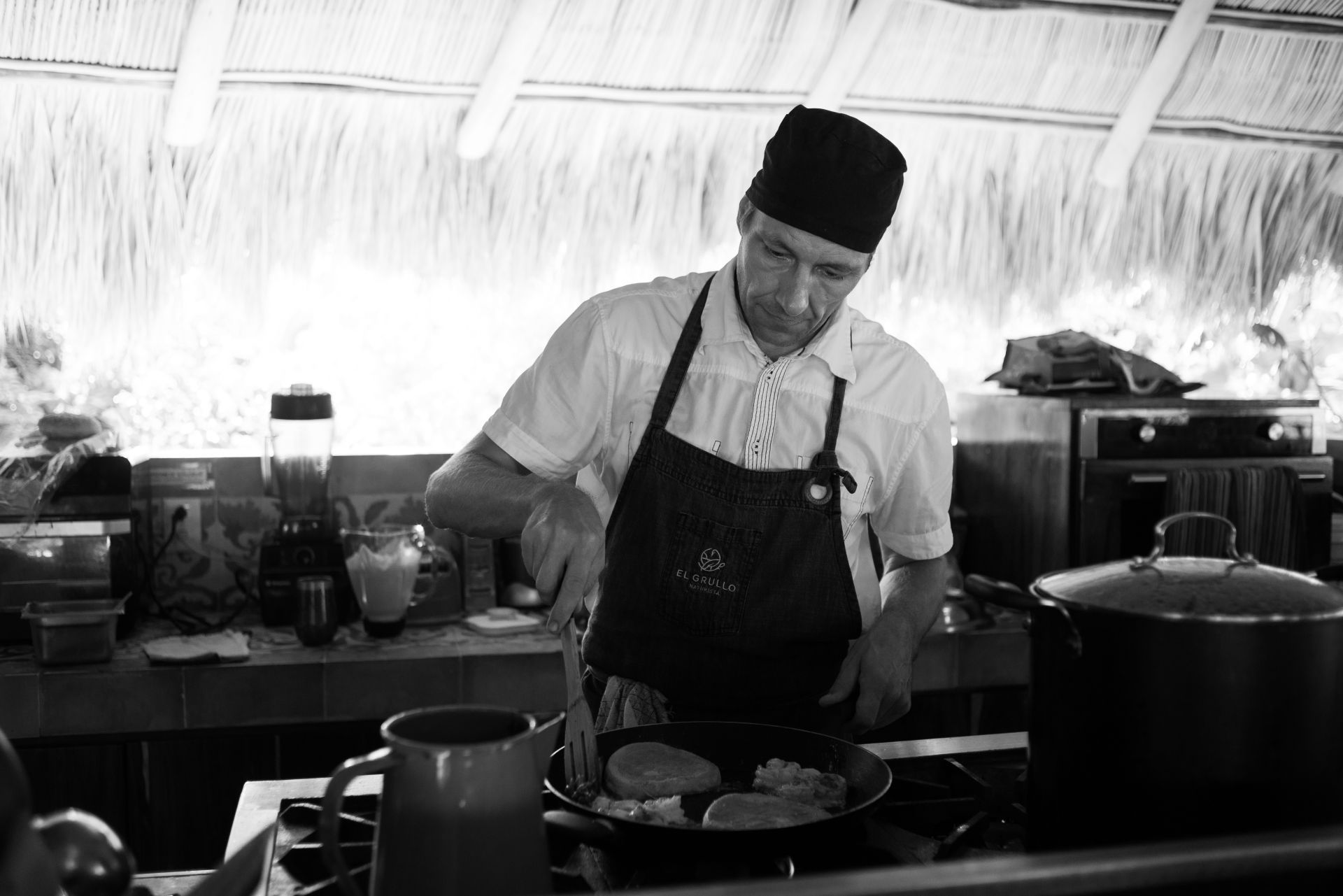 Una fotografía en blanco y negro de un chef preparando comida en una cocina.