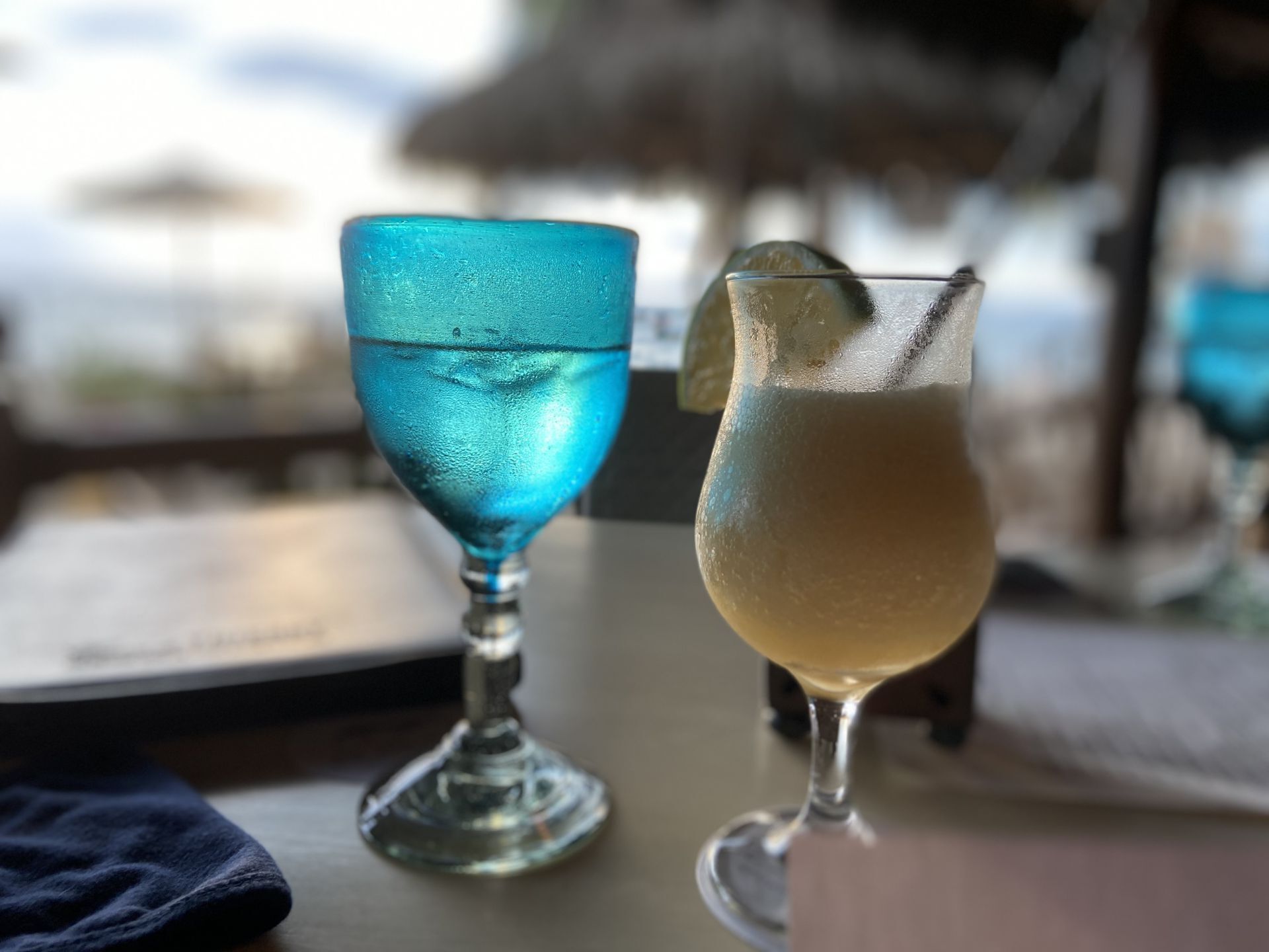 Dos vasos de bebidas en una mesa, uno azul y otro blanco.