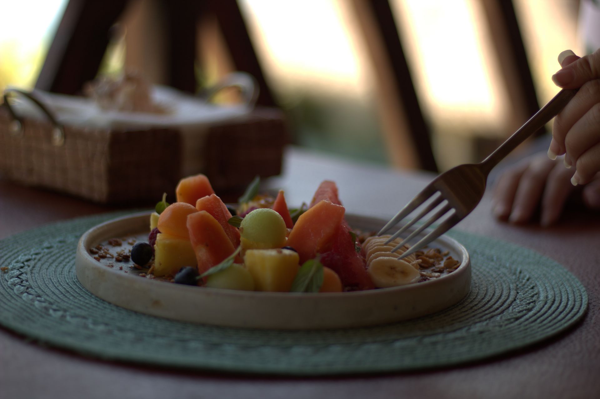 Una persona está comiendo un plato de fruta con un tenedor.