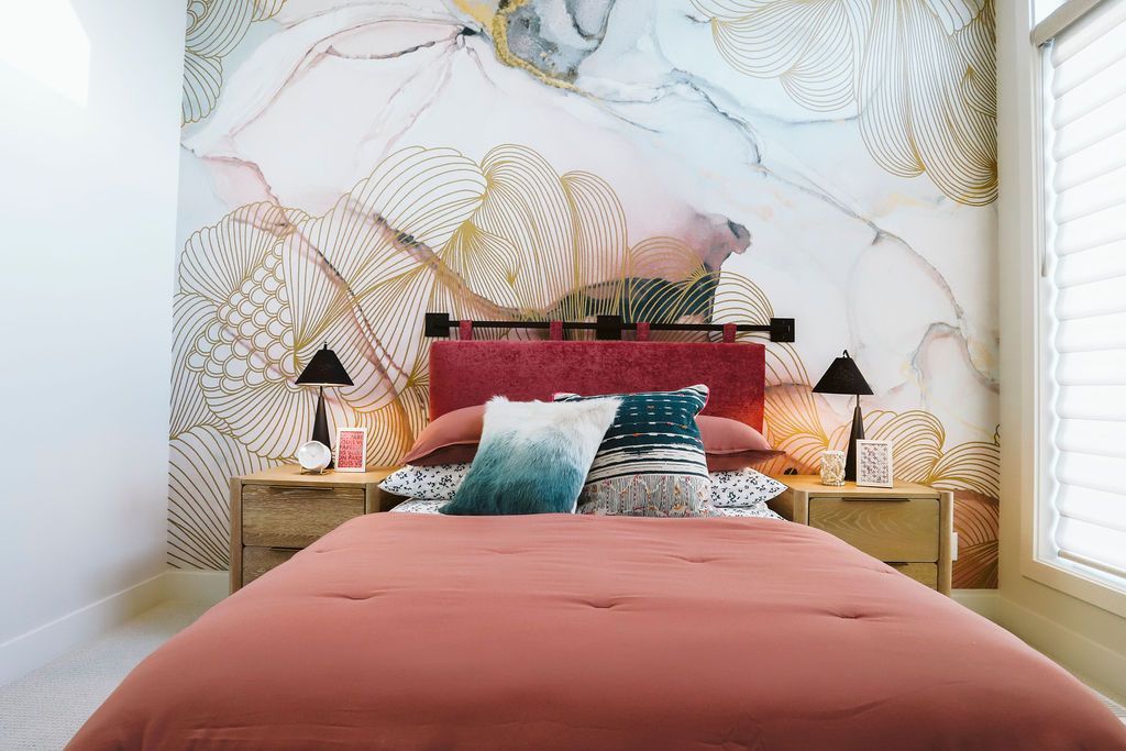 A bedroom with a bed , nightstands , lamps and a large painting on the wall.