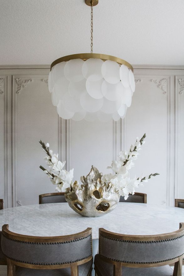 A dining room with a table and chairs and a chandelier hanging from the ceiling.