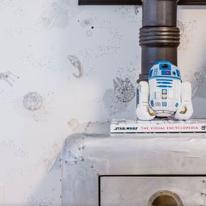 A r2d2 toy is sitting on top of a star wars book