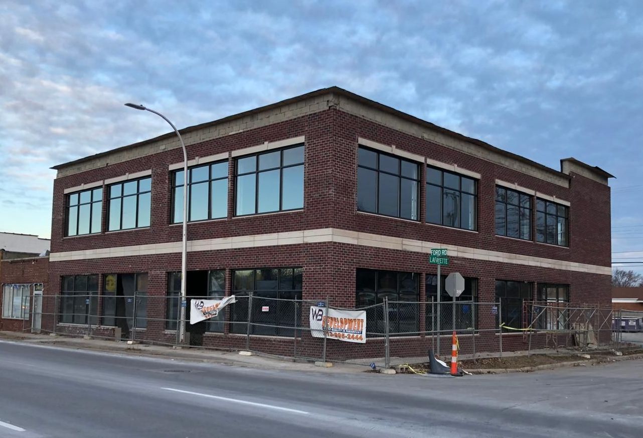 A large brick building is being built on the corner of a street.