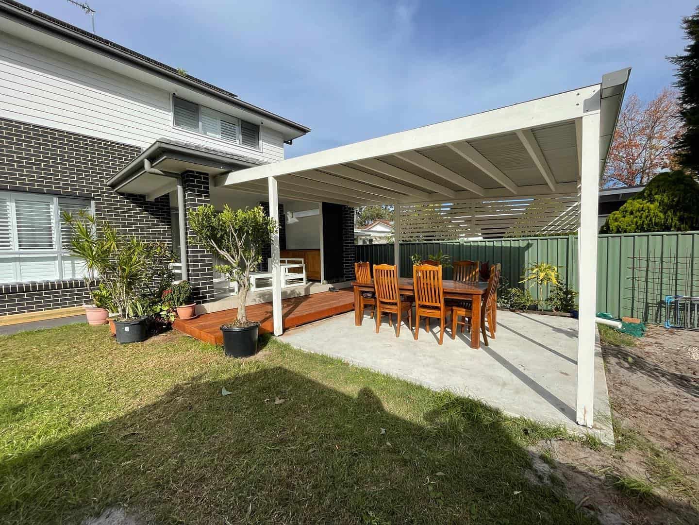 A Table and Chairs Set Under a White Pergola — Pride Carpentry & Maintenance In Berkeley Vale, NSW