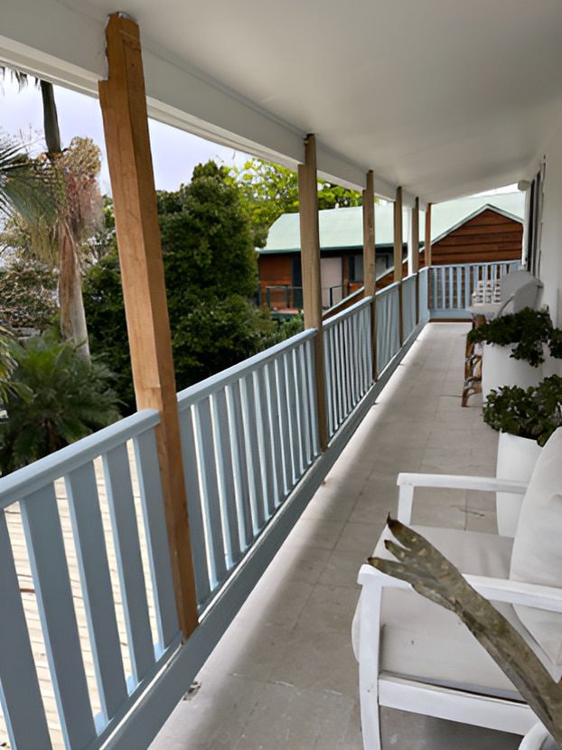 A Balcony With White Chairs and Railing — Pride Carpentry & Maintenance In Berkeley Vale, NSW