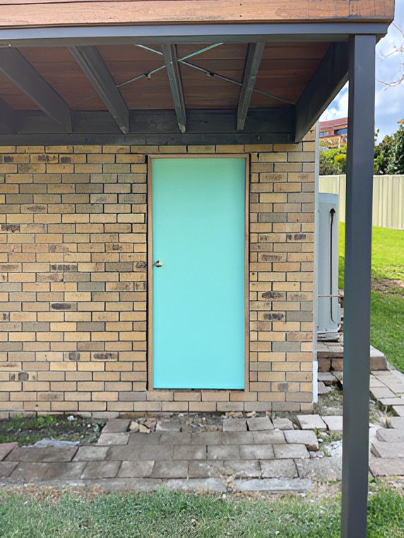 A Blue Door on a Brick Building — Pride Carpentry & Maintenance In Berkeley Vale, NSW