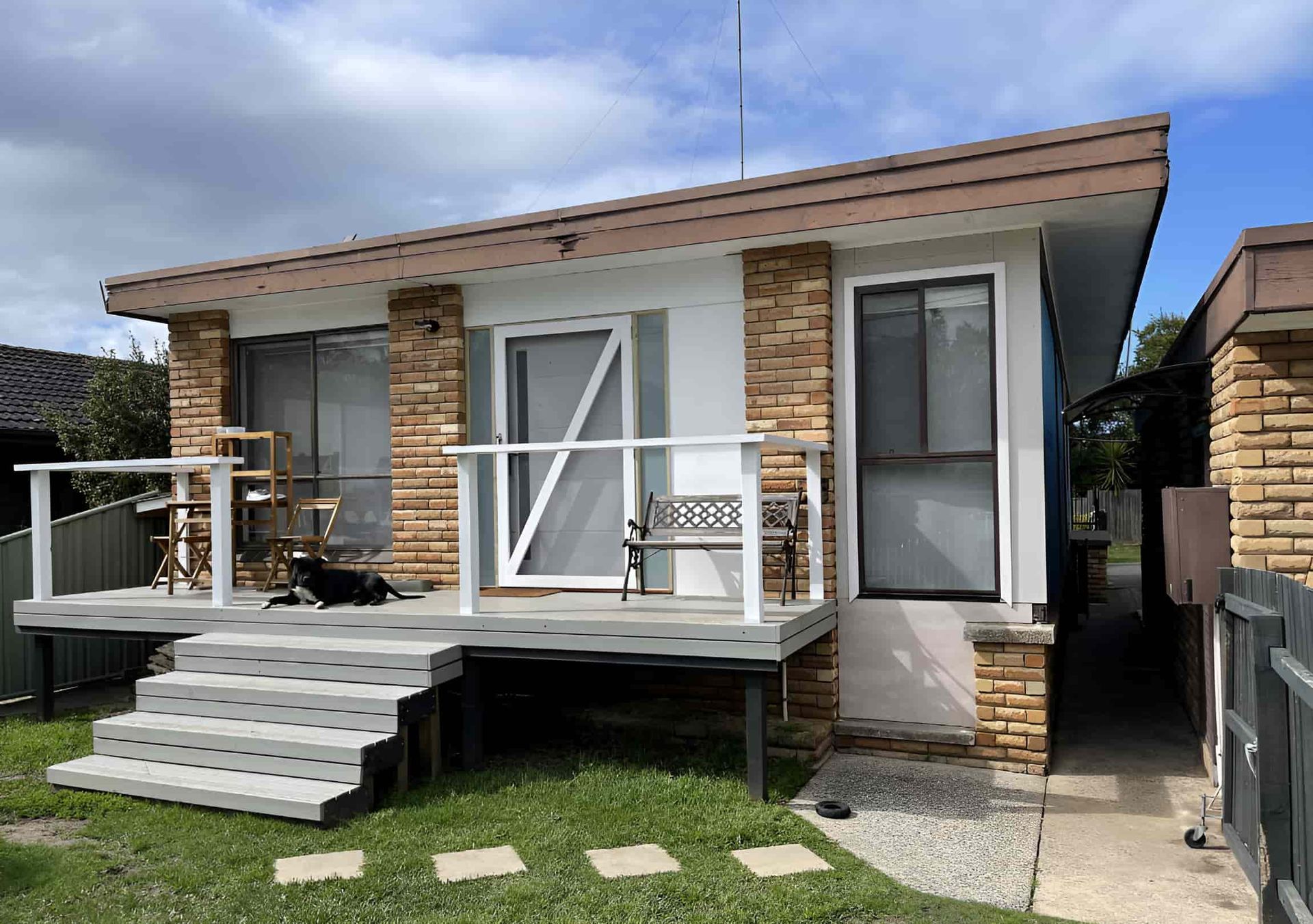A Small Brick House With a Dog on the Porch — Pride Carpentry & Maintenance In Central Coast, NSW