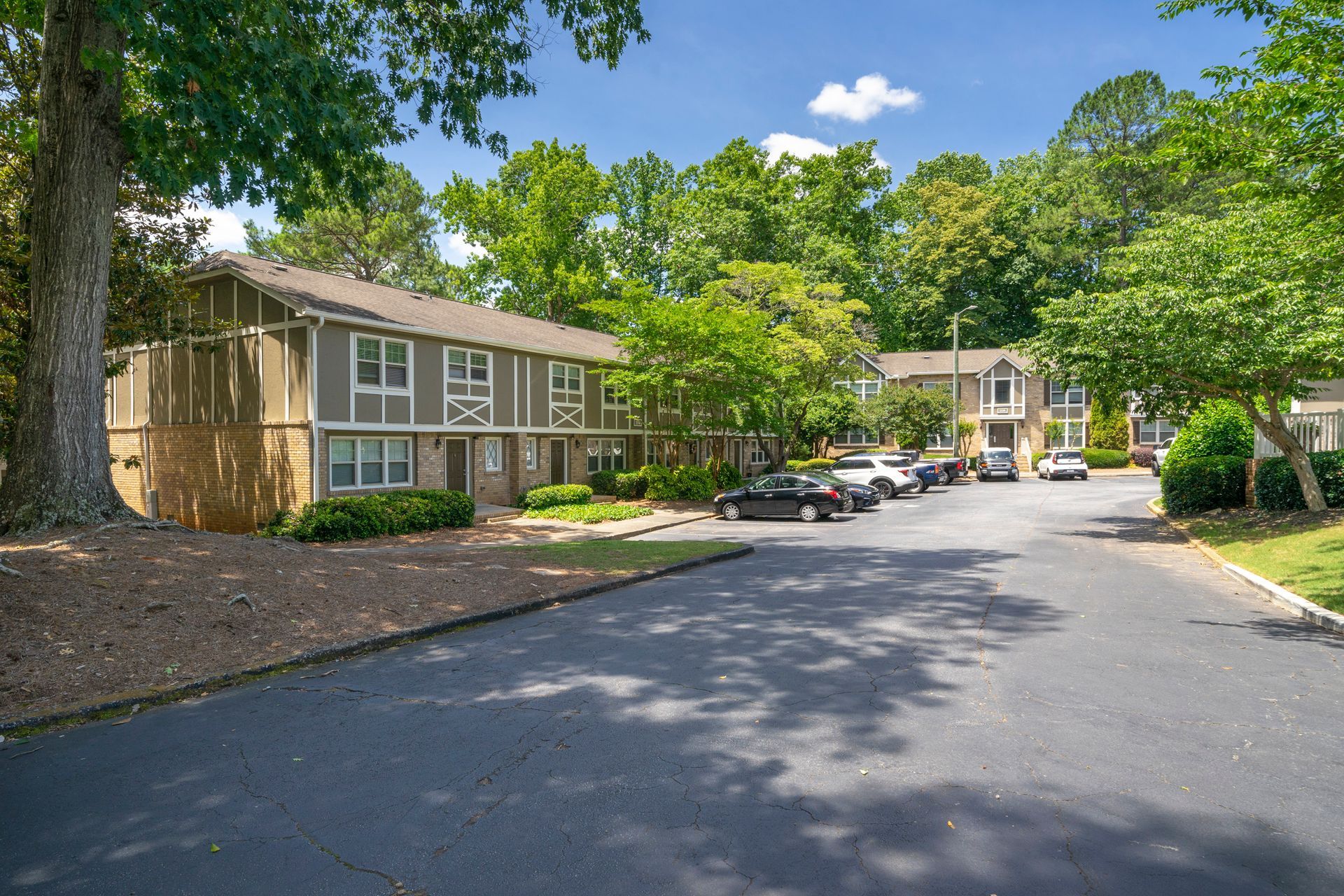 Quiet apartment complex driveway with tan buildings and trees on a sunny day