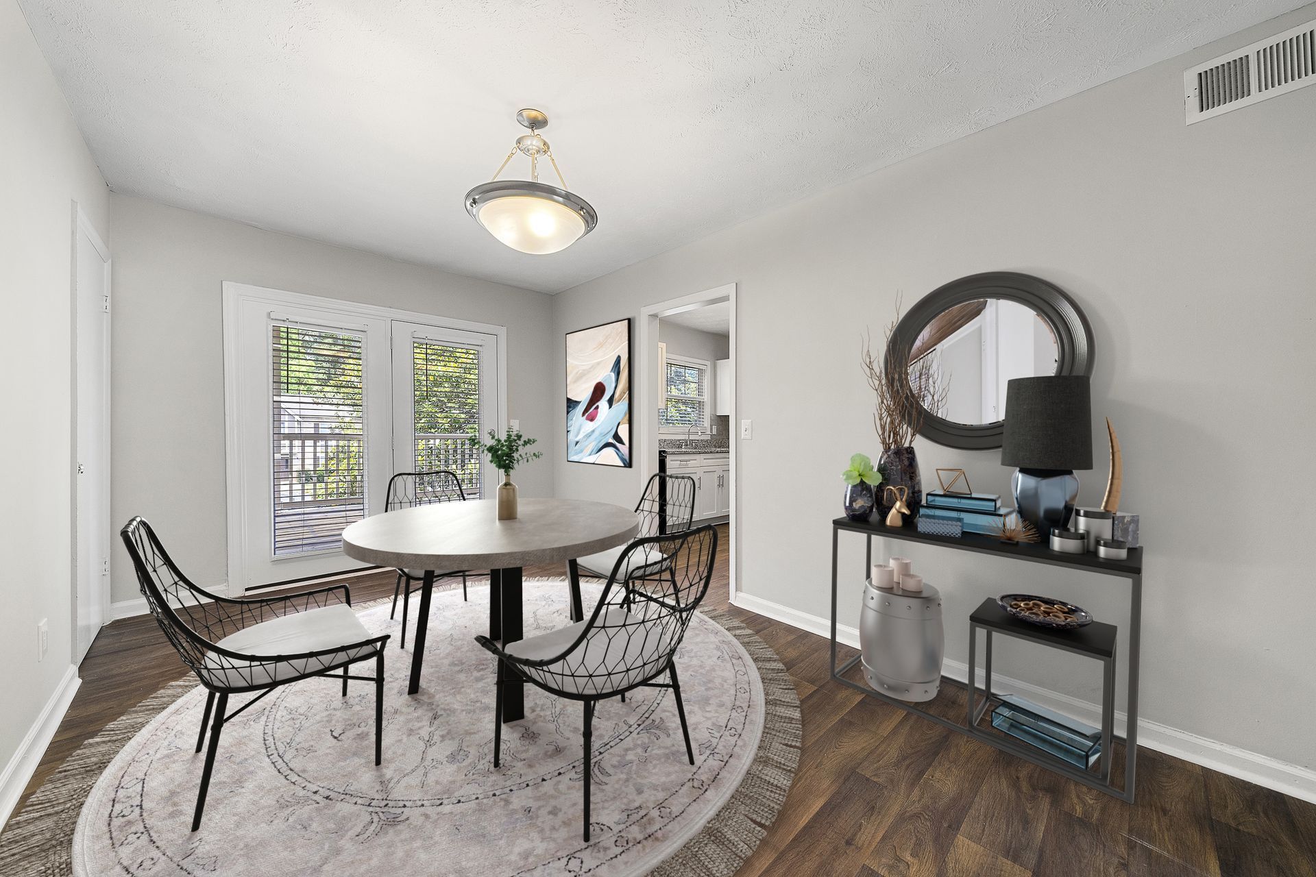 Bright dining room with round table, wicker chairs, rug, console table, and glass French doors