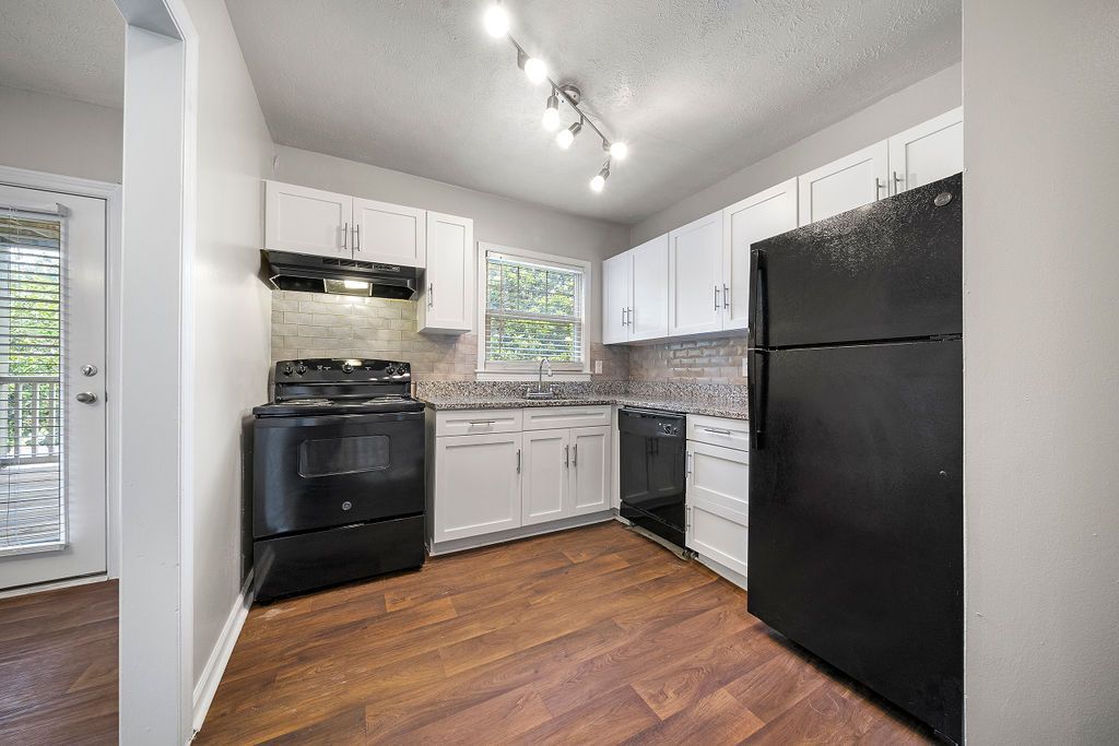 Kitchen with black appliances and white cabinets at crossing at henderson mill 