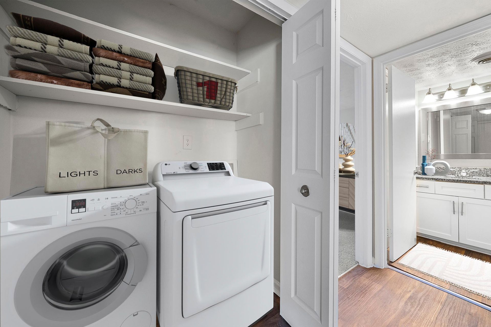 Laundry room with a washer, dryer, shelves of folded towels, and a doorway to a bathroom