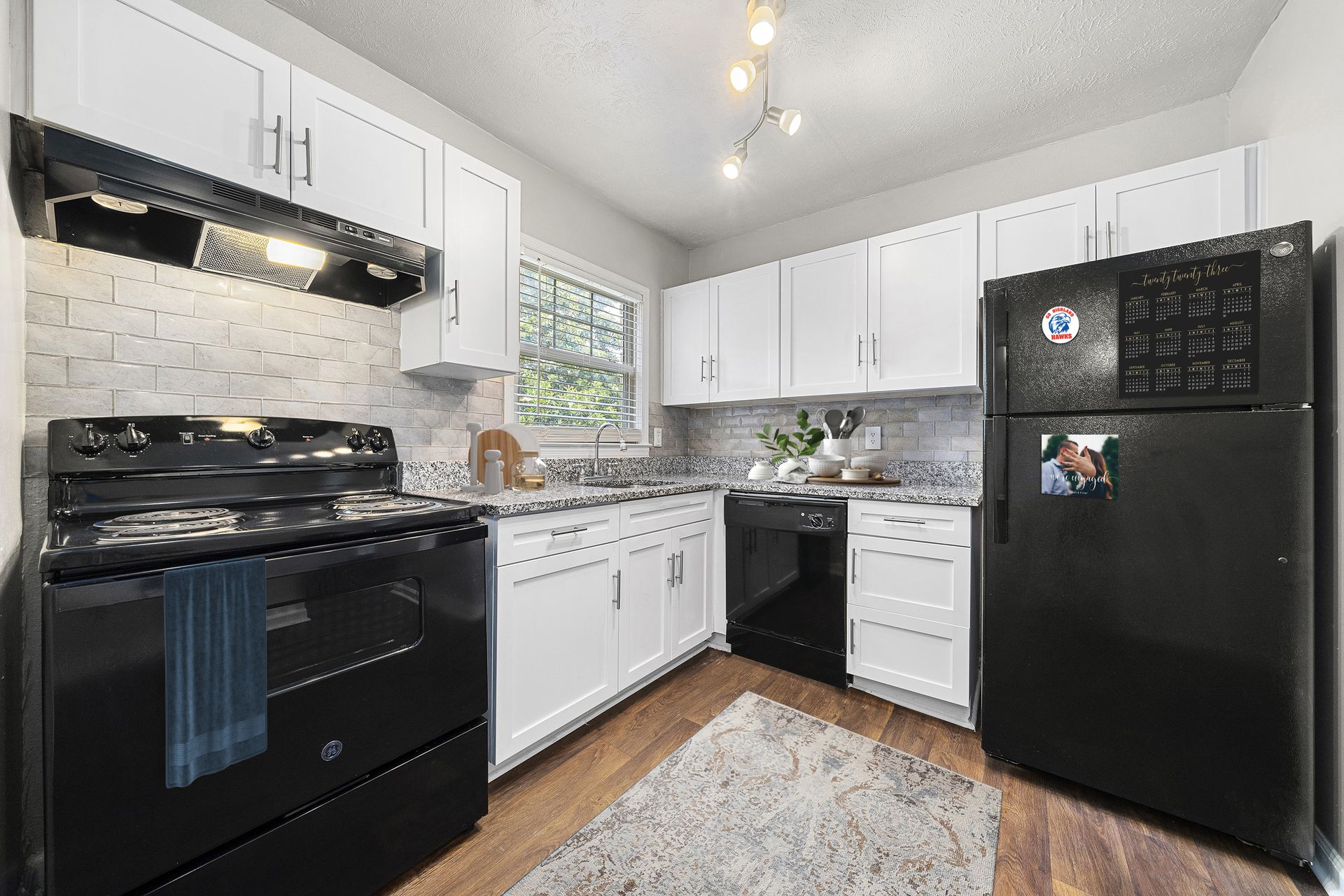Bright kitchen with white cabinets, black appliances, and a small window over the sink
