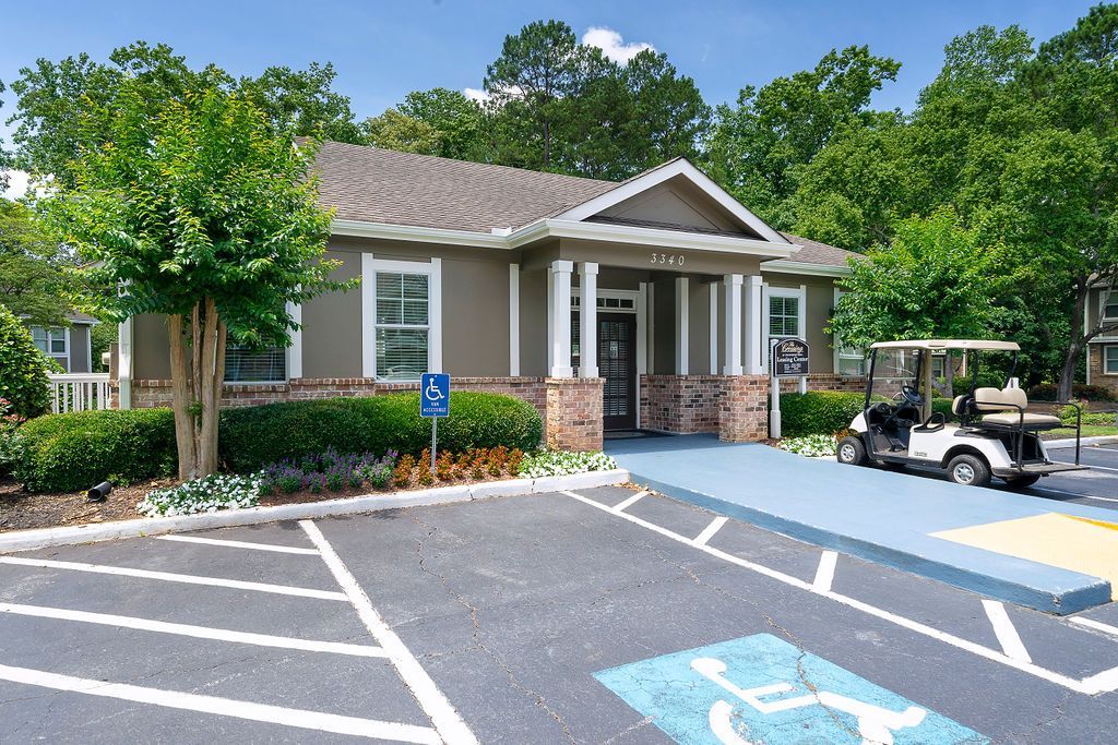 Accessible parking spaces in front of a small building with trees and a golf cart nearby