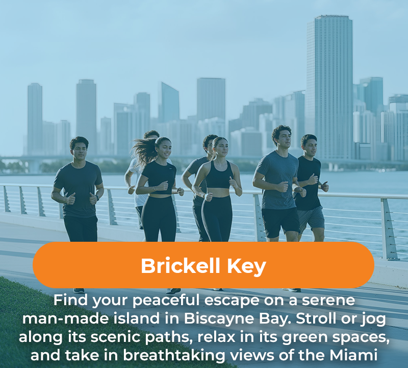 People jogging on a path along the water in front of a city skyline, Brickell Key in Miami.