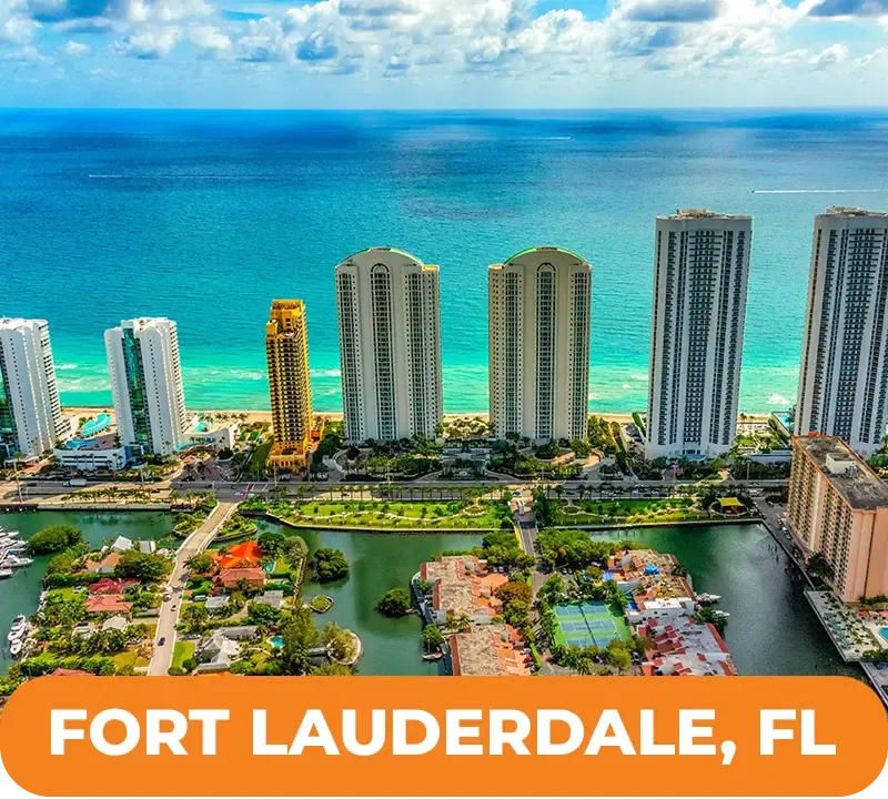 Aerial view of Fort Lauderdale, Florida, with tall beachfront buildings, ocean, and waterways.