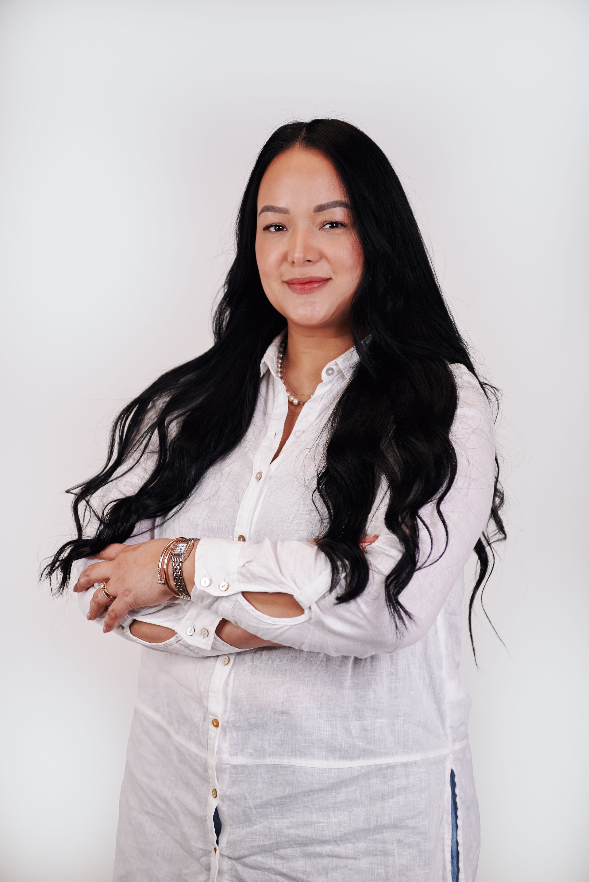 A woman is sitting on a stool wearing a white shirt and jeans.