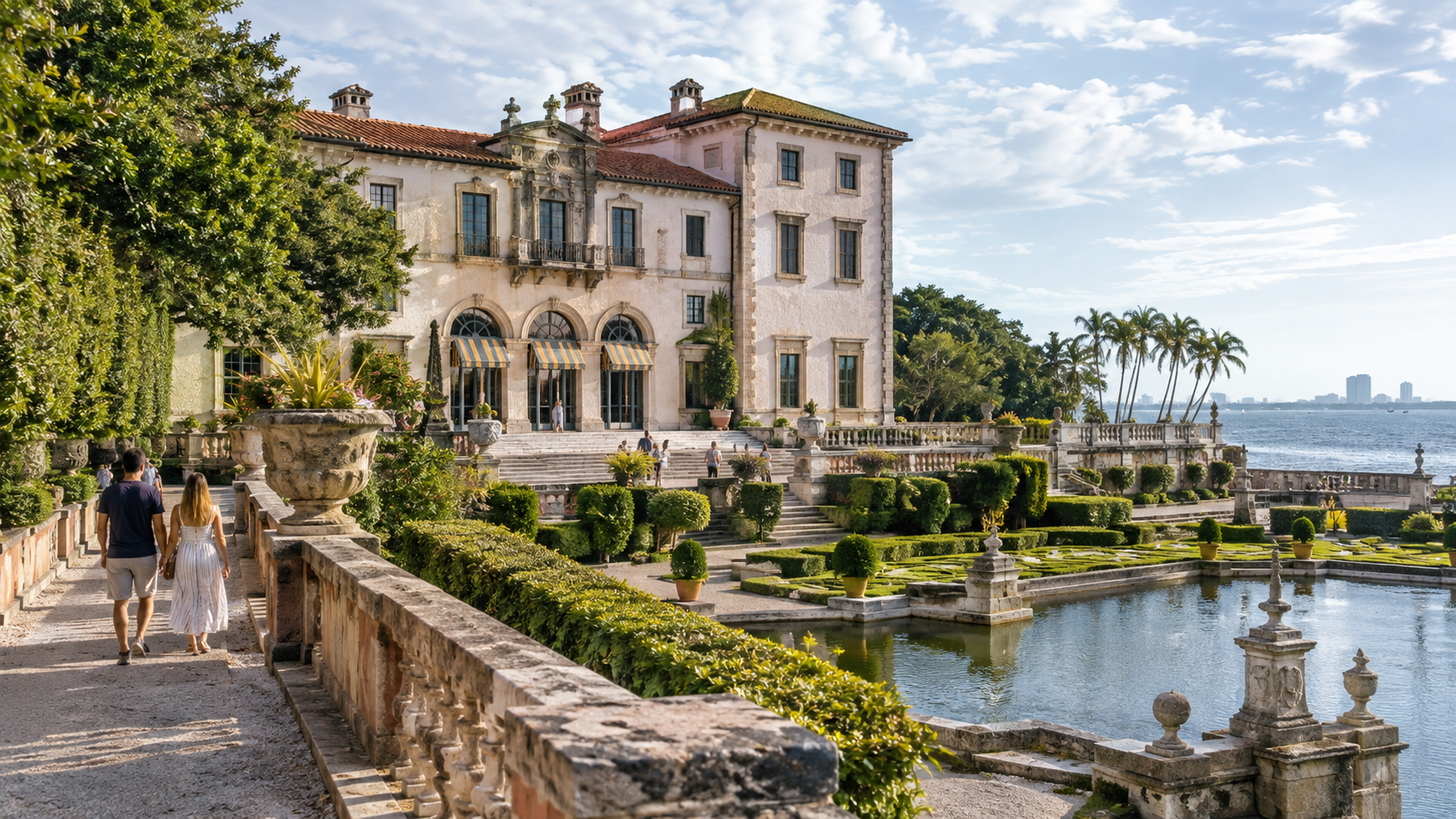 Vizcaya miami - Historic villa with arched terraces beside a waterfront garden, with people walking along the path.