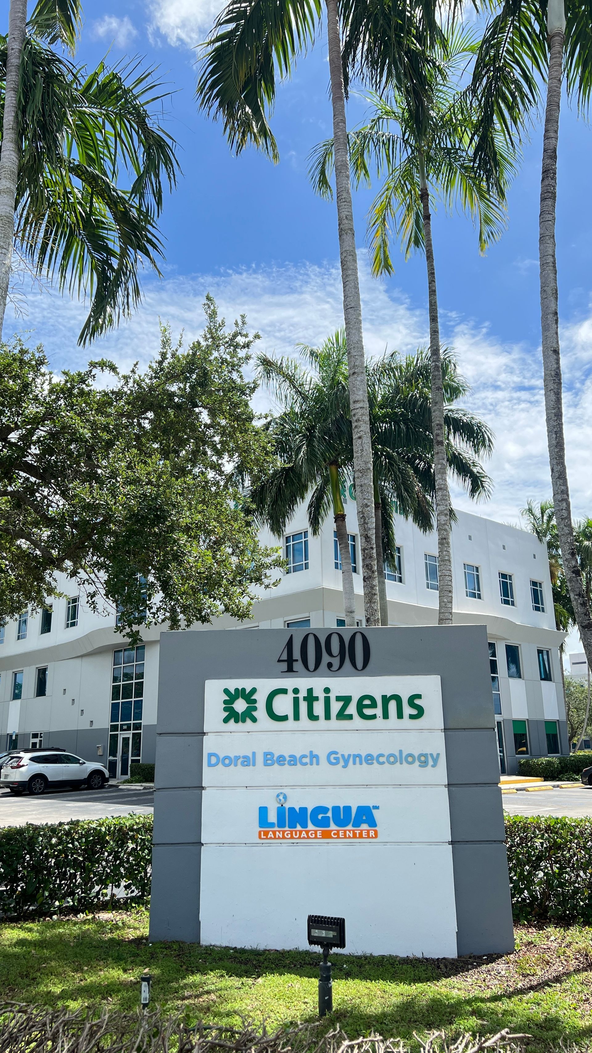 Citizens sign outside a white office building with palm trees and blue sky.