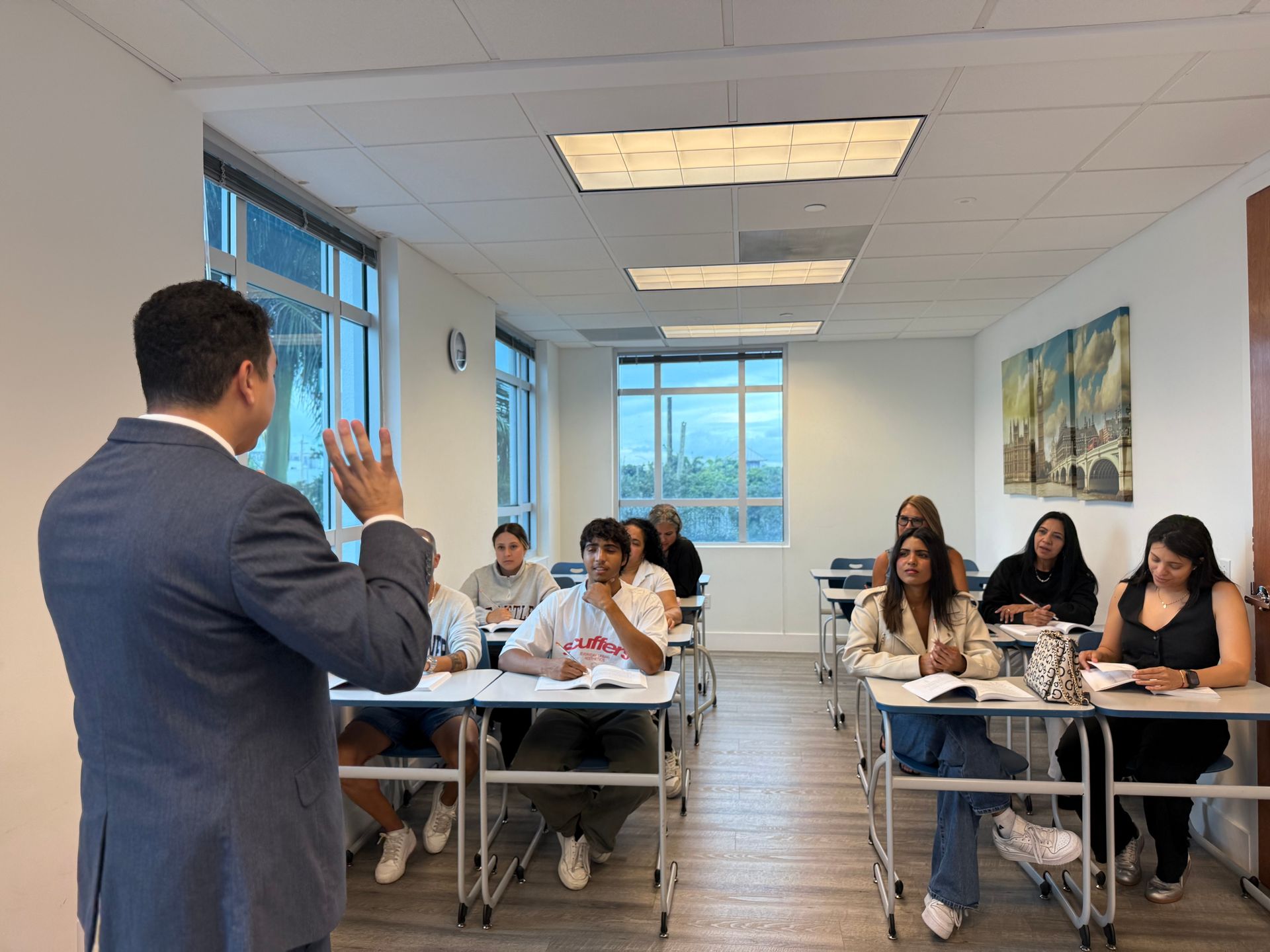 Instructor speaking to a classroom of seated students in a bright office-style training room