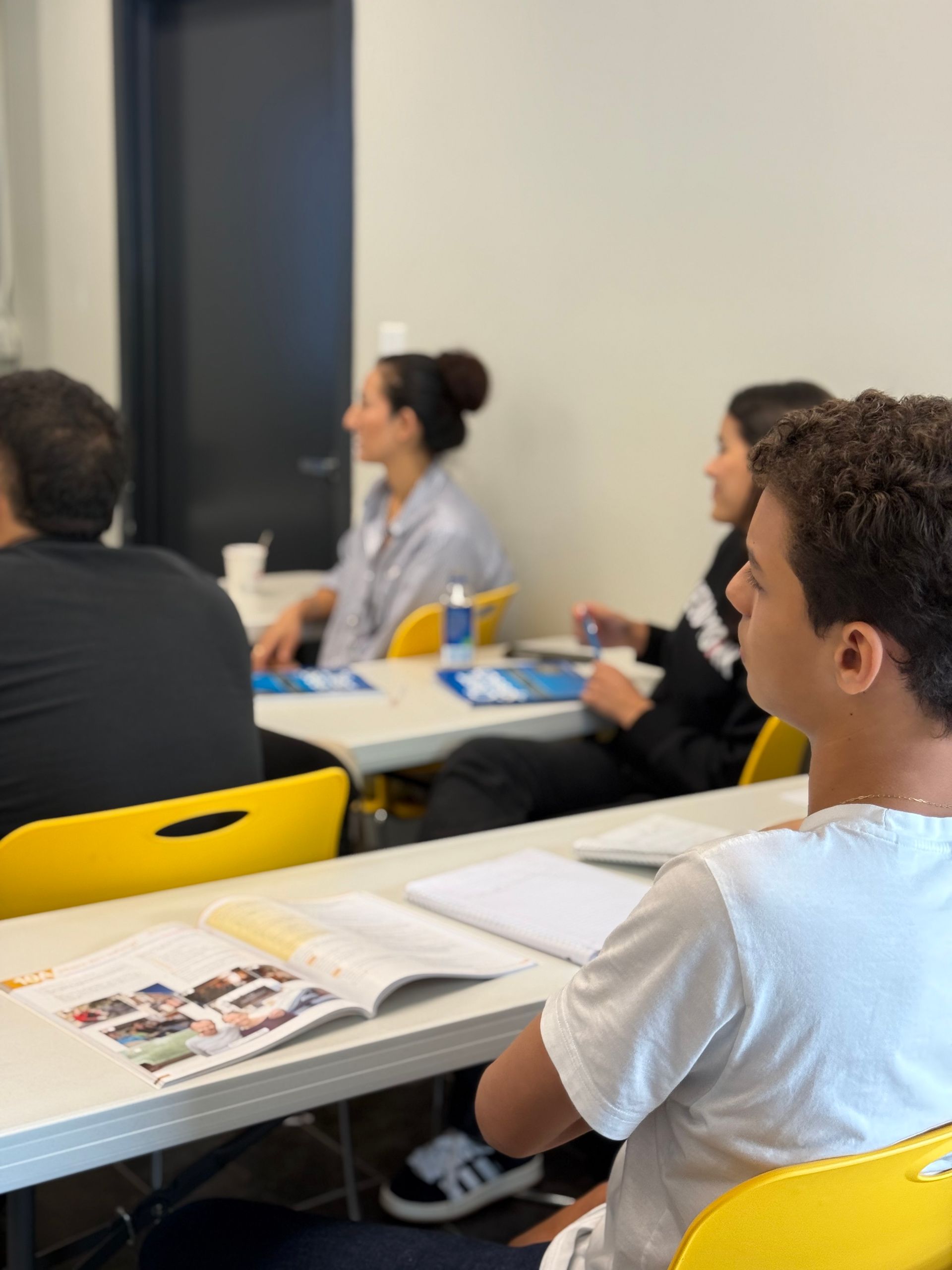 Students seated in a classroom, listening during a lecture with notebooks and papers on desks