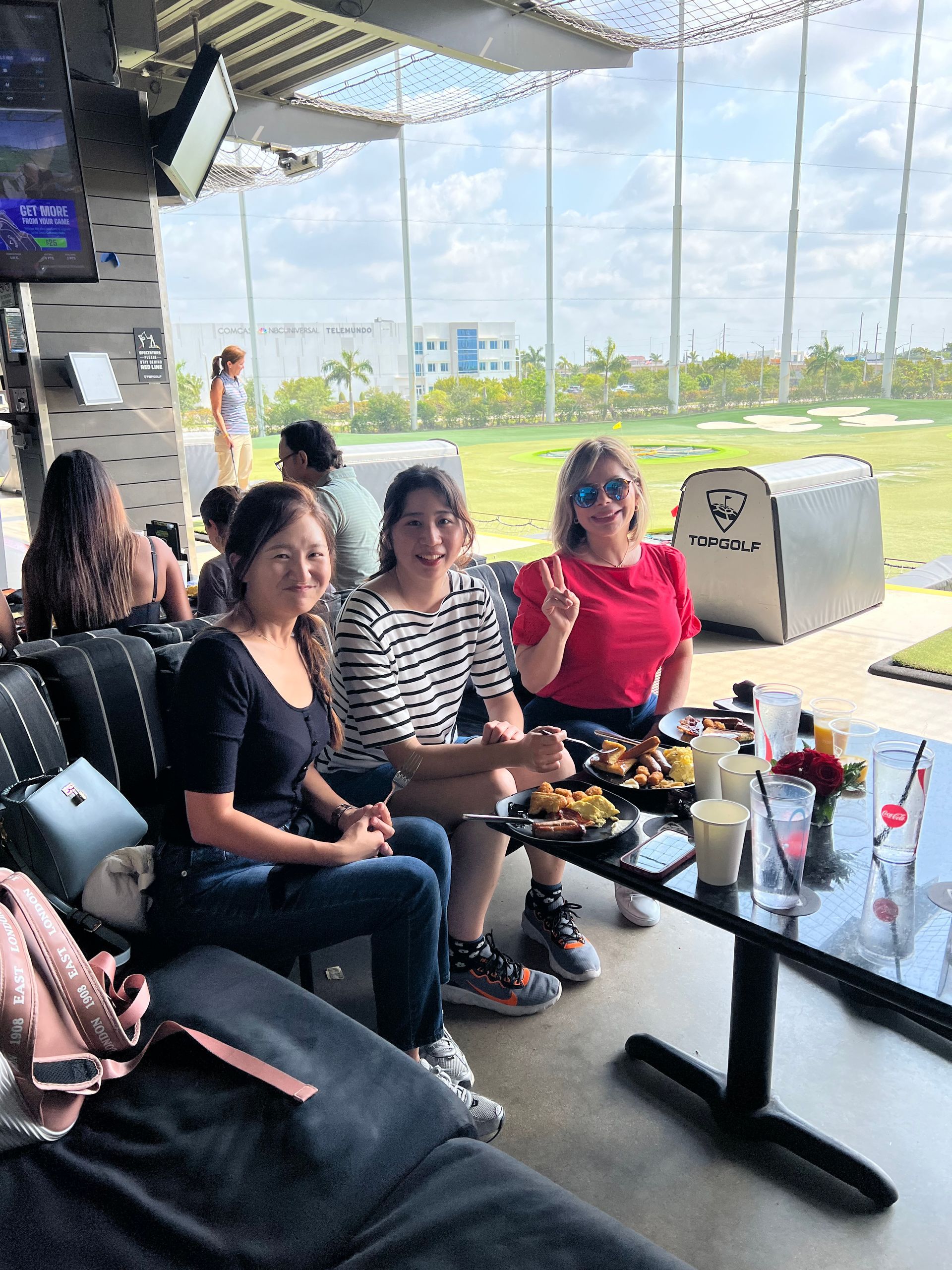 Friends seated at an outdoor café, chatting beside a table with drinks and snacks.